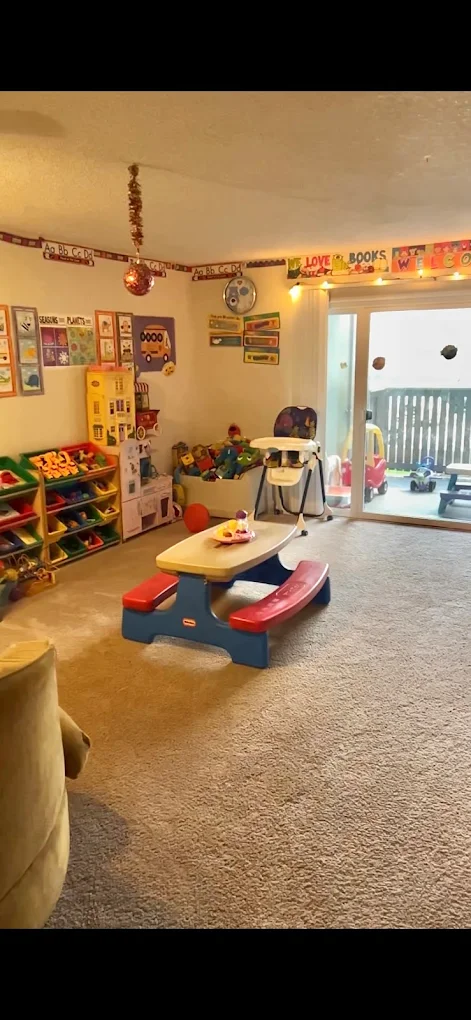 The main indoor play area at Ana's Day Care with a children's picnic table, toy shelves and learning materials