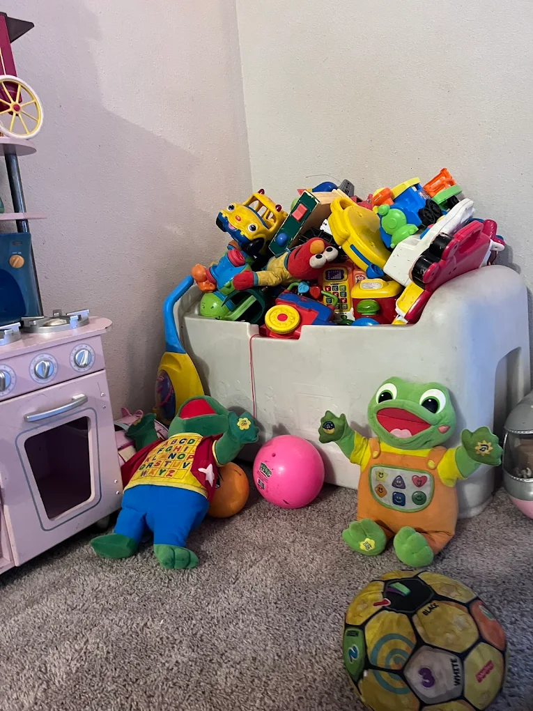 Toy chest full of toddler toys with plush animals and a play kitchen